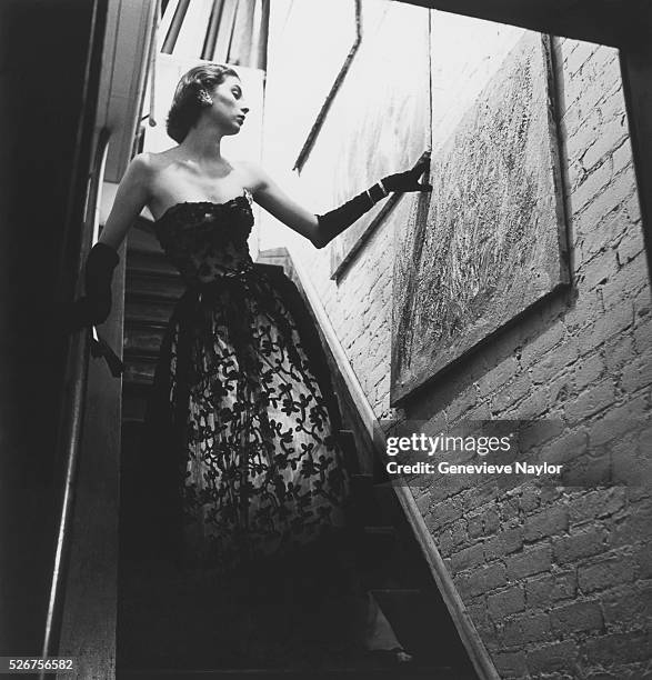 Actress Suzy Parker models a black chenille evening gown with netting designed by Adrian.