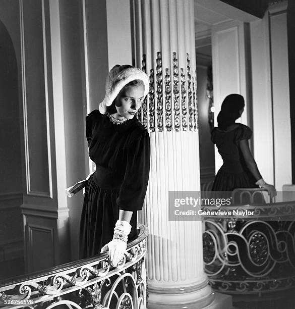 Model wears a blue crepe evening dress of Forstmann Wool, a fur hat by John Frederics and jewelry by Hattie Carnegie. New York, 1946.