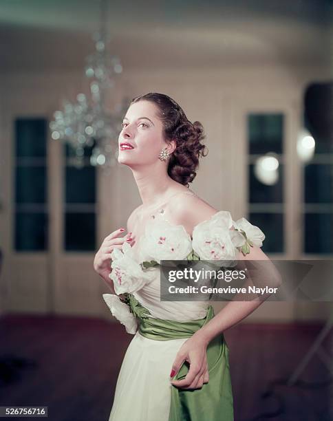 Woman models a gown with large roses around the bodice.