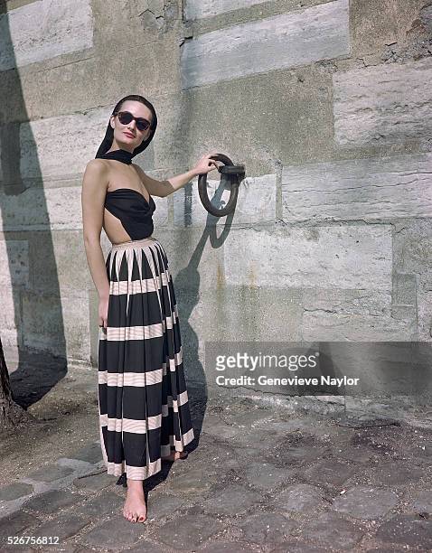 Woman models a dress by Balmain on an embankment of the Seine.