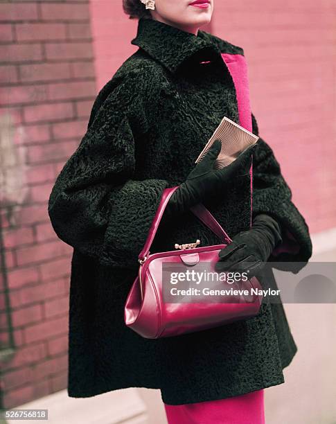 Woman models a black jacket and red purse by Pauline Trigere.