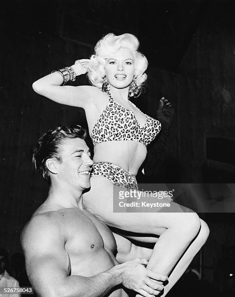 Actress Jayne Mansfield wearing a leopard print bikini, sitting on the shoulder of her husband Mickey Hargitay, at a Hollywood costume party,...