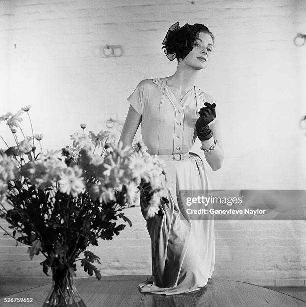 Model-actress Suzy Parker wears a day dress, modeling next to a bouquet of daisies.