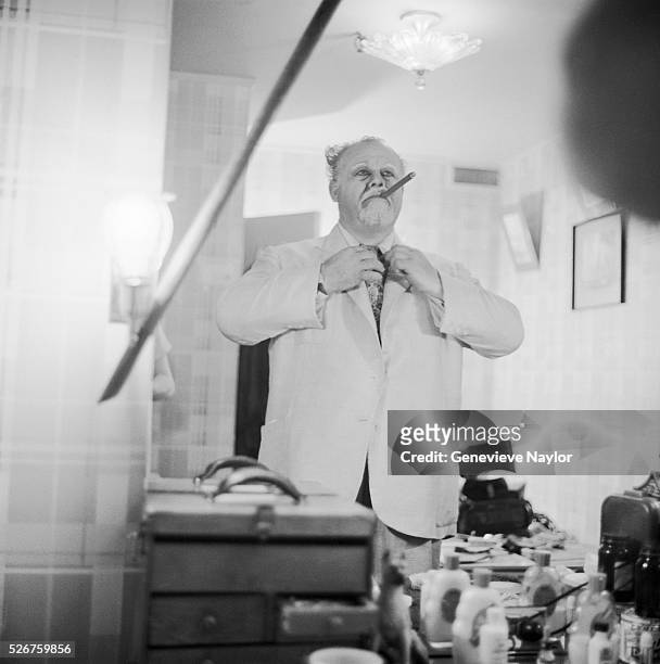 Actor Burl Ives smokes a cigar and adjust his tie in the dressing room for his role as "Big Daddy" in the Broadway production of Tennessee William's...