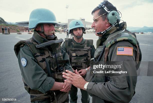 French United Nations Peacekeepers and a U.S. Air Force pilot talk while cargo is unloaded quickly to avoid sniper fire from across the runway....