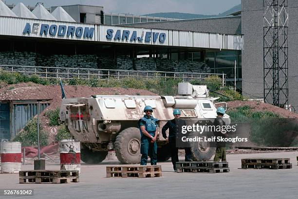 French United Nations Peacekeepers and a local policeman stand by an armored U.N. Vehicle ready to unload cargo quickly from a United States Air...