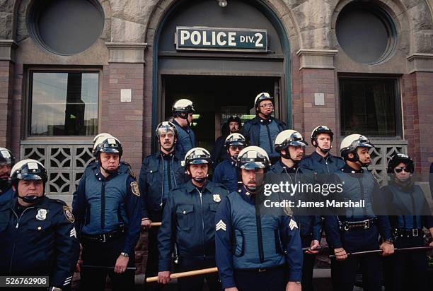 Police officers wearing protective gear and brandishing nightsticks gather outside a police station during the Tawana Brawley demonstration.