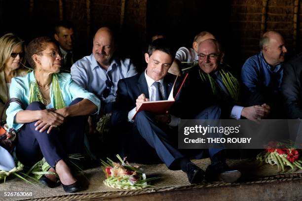 French Prime Minister Manuel Valls signs a guestbook next to French Overseas Minister George Pau-Langevin during a meeting with Hnatalo traditional...