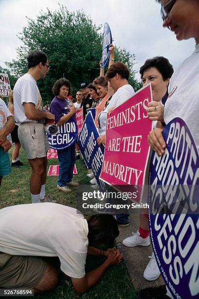 Pro-life protester kneels at the foot of a pro-choice protester and prays during a pro-choice demonstration outside a pregnancy center in Little...
