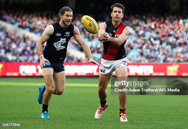 Jonathan Simpkin of the Bombers handpasses the ball ahead of Bryce Gibbs of the Blues during the 2016 AFL Round 06 match between the Carlton Blues...