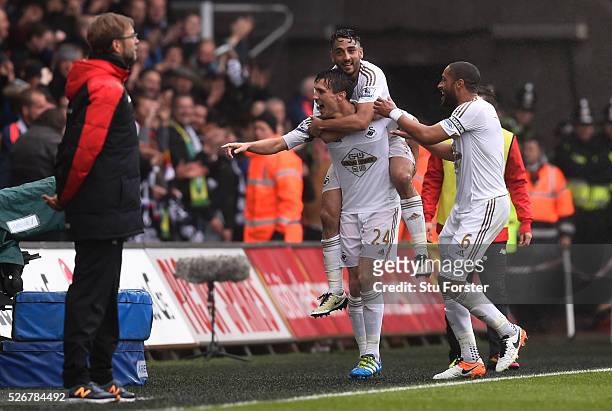 Jack Cork of Swansea City celebrates scoring his team's second goal with Neil Taylor and Ashley Williams as Jurgen Klopp, manager of Liverpool looks...