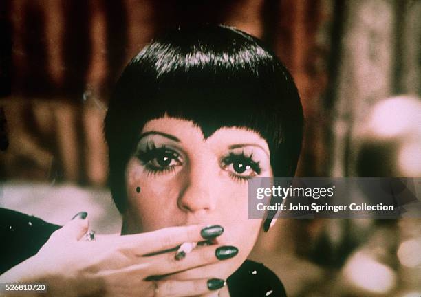 Close-up of Liza Minnelli wearing a pixie haircut and green nailpolish. Minelli is smoking a cigarette in this movie still from Bob Fosse's film of...