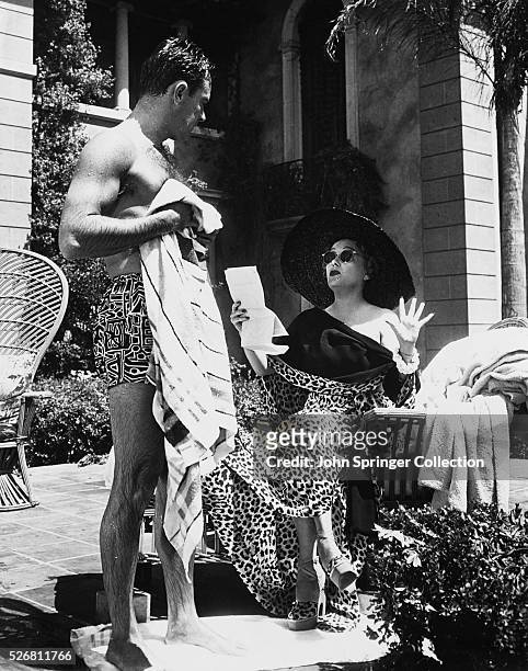William Holden as Joe Gillis and Gloria Swanson as Norma Desmond talk by the pool during the filming of the 1950 film Sunset Boulevard.