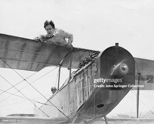 Harvey Hanford lays atop a plane's wings in a scene from the silent drama film, 'The Grim Game', directed by Irvin Willat, 1919.