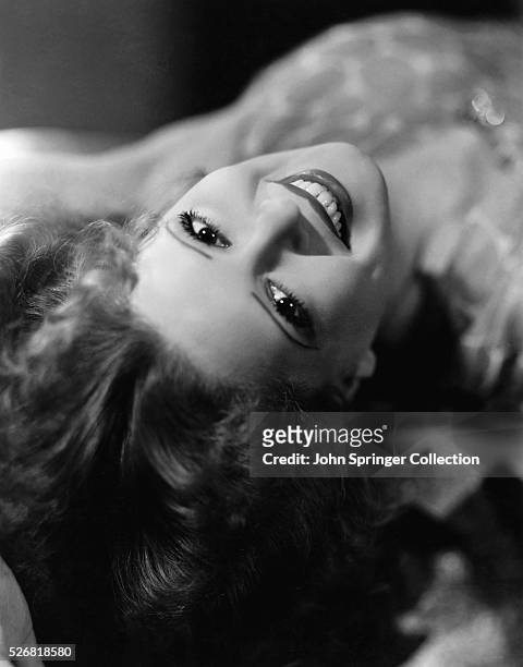Actress Clara Bow smiles while lying down.