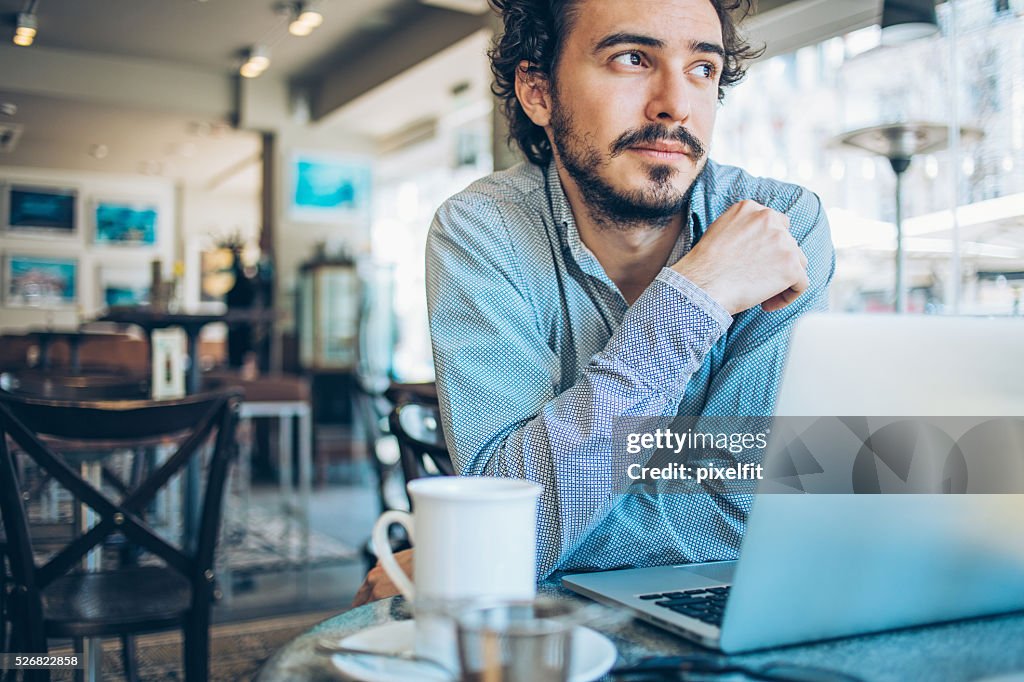 Man with laptop and hot drink in a restaurant