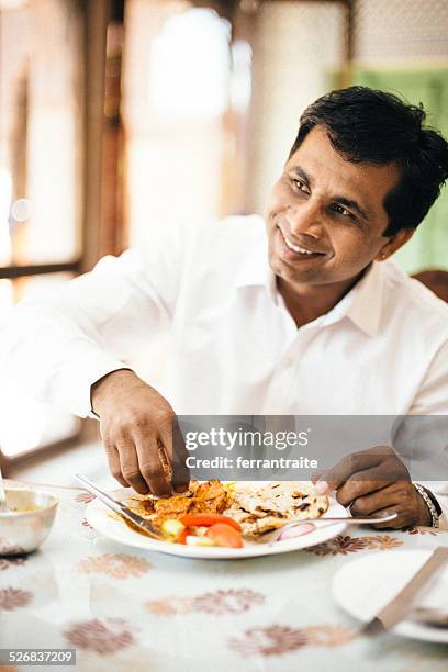 real indian man eating with hands in indian restaurant - chicken fingers stockfoto's en -beelden