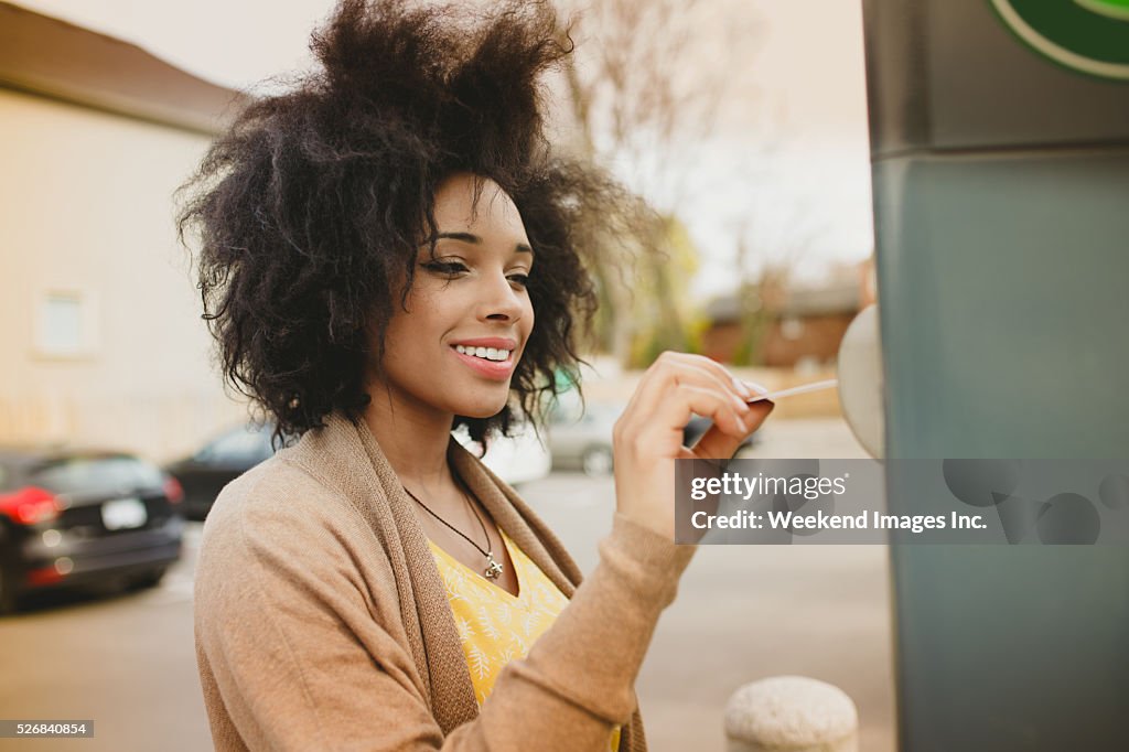 Woman paying with credit card on parking meter