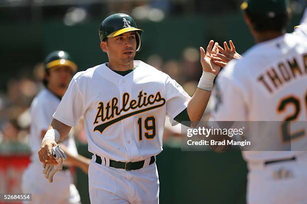 Marco Scutaro of the Oakland A's is greeted by teammates during the game against the Los Angeles Angels of Anaheim at McAfee Coliseum on April 17,...