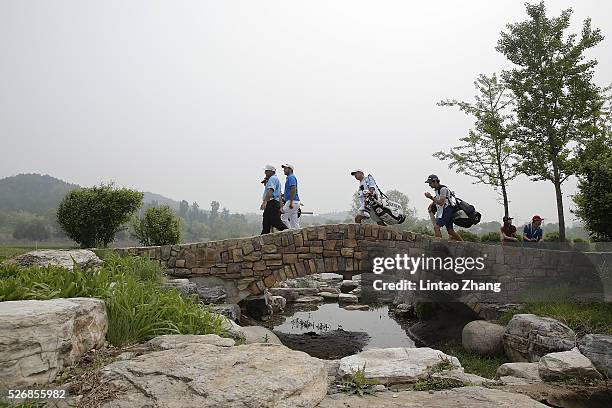 Alexander Levy of France walk with Hennie Otto of South Africa during the final round of the Volvo China open at Topwin Golf and Country Club on May...