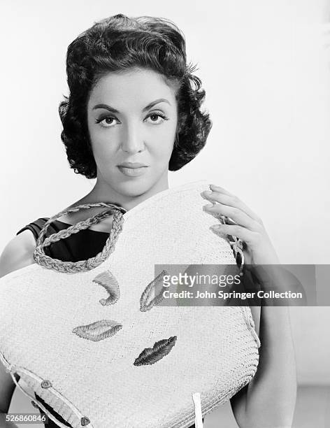Actress Katy Jurado shows off a purse embroidered with a stylized face.