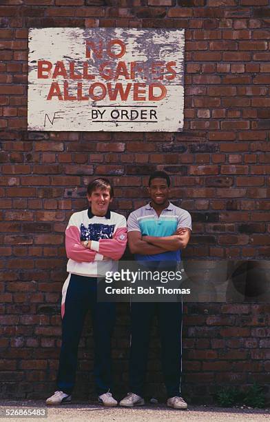 Liverpool footballers John Barnes and new signing Peter Beardsley, outside Anfield football stadium in Liverpool, 1987. Above them is a sign reading:...