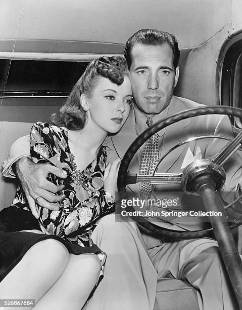 Fugitive Roy Earle holds onto Marie Garson as the pair drive in the 1941 film noir crime film High Sierra.