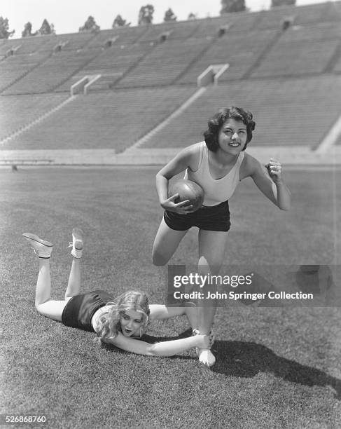 Paramount actresses Virginia Bruce and Lillian Roth play football at a football stadium. Bruce and Roth both starred in films primarily from the...