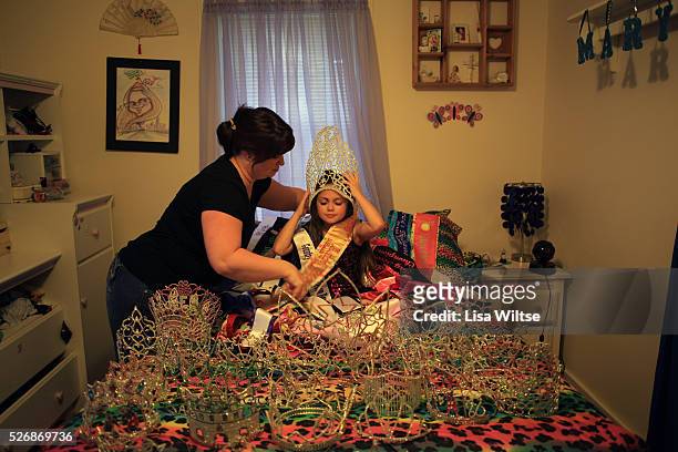 Helps prepare her daughter MB for a portrait in her bedroom surrounded by 57 crowns and sashes which she won at beauty pageants on October 18, 2012....