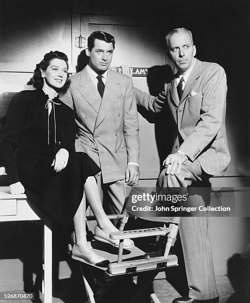 Actress Rosalind Russell sits beside actor Cary Grant and film director Howard Hawks, as the trio watches Ralph Bellamy shoot a scene for his...