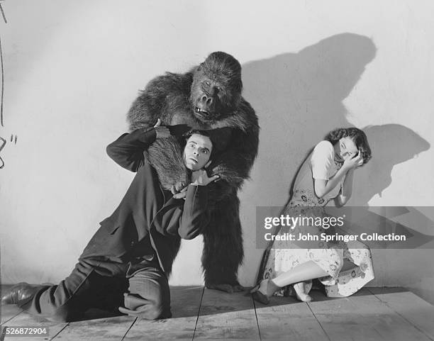 Susan Webster cowers in horror as a gorilla monster chokes a man in the 1941 sci-fi horror film The Monster and the Girl.