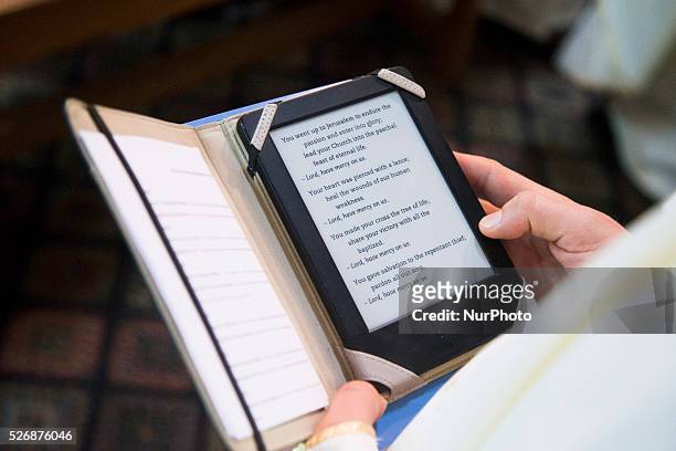 Catholic priest reads an electornic version of the Book of the Gospels during the celebration of the Holy Thursday mass the Church of the Holy...