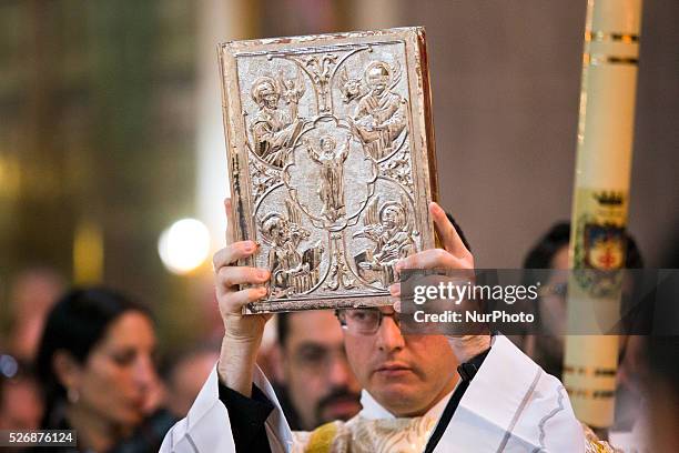 Catholic priest holds the Book of the Gospels during the celebration of the Holy Thursday mass the Church of the Holy Sepulchre in the Old City of...