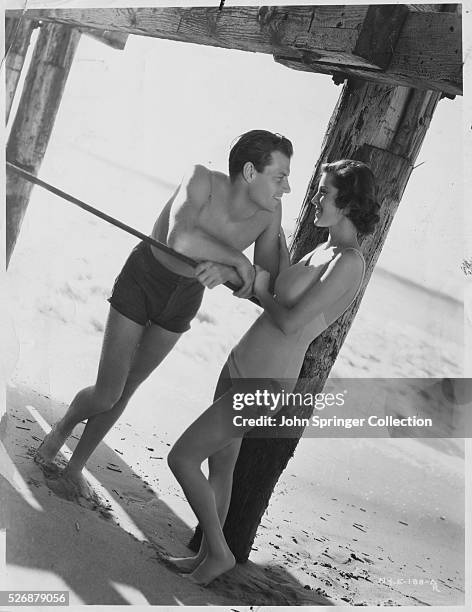 Newlywed actors Joel McCrea and Frances Dee stand together under a Santa Monica pier.