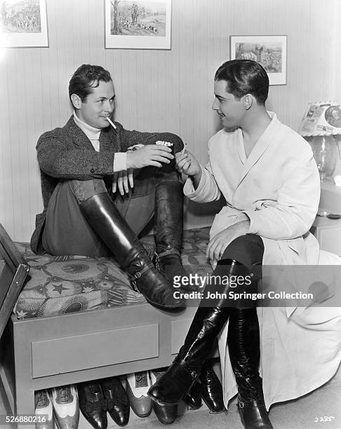 Ramon Novarro visits Robert Montgomery's dressing room for a cigarette.