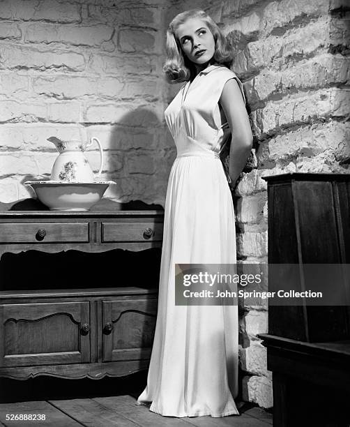 Actress Lizabeth Scott models the nightgown she wears as Paula Haller in the 1947 film Desert Fury. The gown, designed by Edith Head, is made of...
