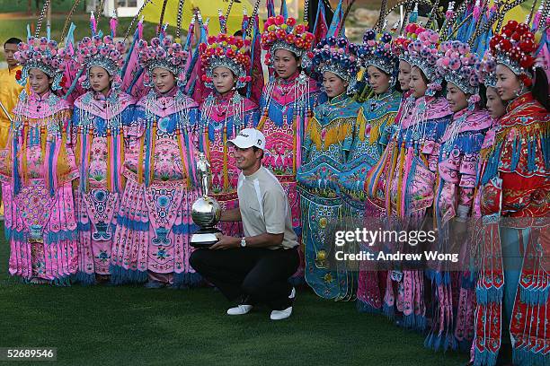 Adam Scott of Australia displays the trophy as he poses with Chinese entertainers after winning the Johnnie Walker Classic at Pine Valley Golf Resort...