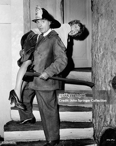 Charles Boyer carrying Margaret Sullavan over his shoulder, despite her wild protests, to demonstrate the technique of a volunteer fireman as...