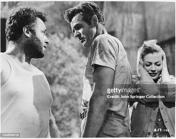 Vasquez and Bill exchange words as Rena covers her ears and hides behind Bill in the 1956 film Back from Eternity.
