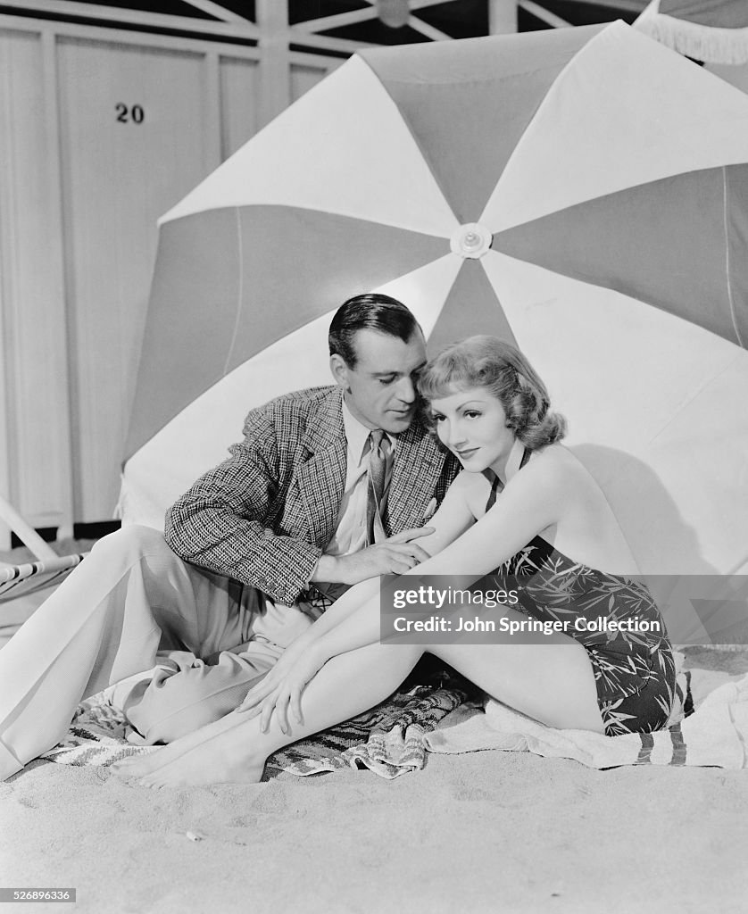 Gary Cooper and Claudette Colbert Seated Under Umbrella