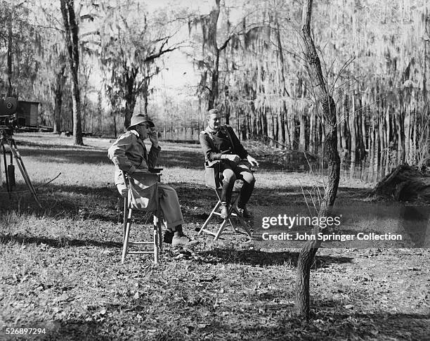 Actor John Wayne and Director John Ford sit and talk while on location for the film The Horse Soldiers.