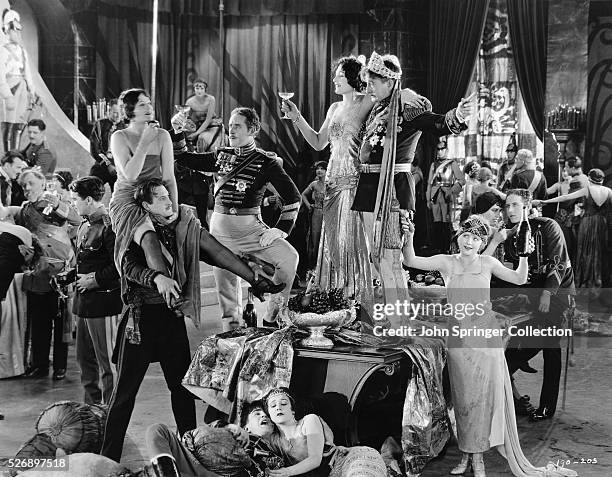 Celebratory scene from the 1924 film Three Weeks features John Sainpolis as The King and Claire de Lorez as Mitz, both of whom are standing on the...