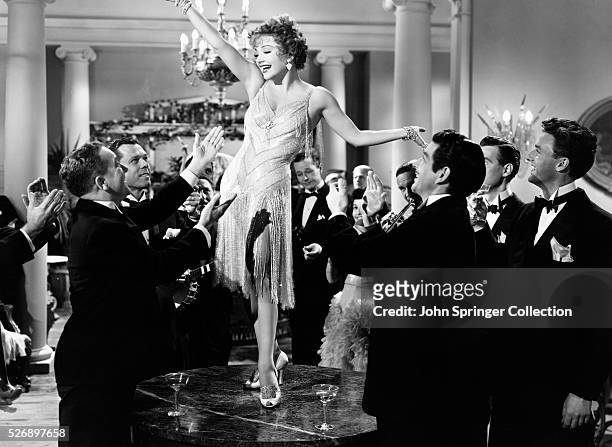 Anne Baxter's character Hannah Adams stands on a table to the delight of appreciative men in a party scene from the 1949 film You're My Everything.