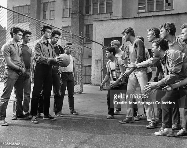 Rival gang members face off in a play yard in a publicity still for West Side Story.