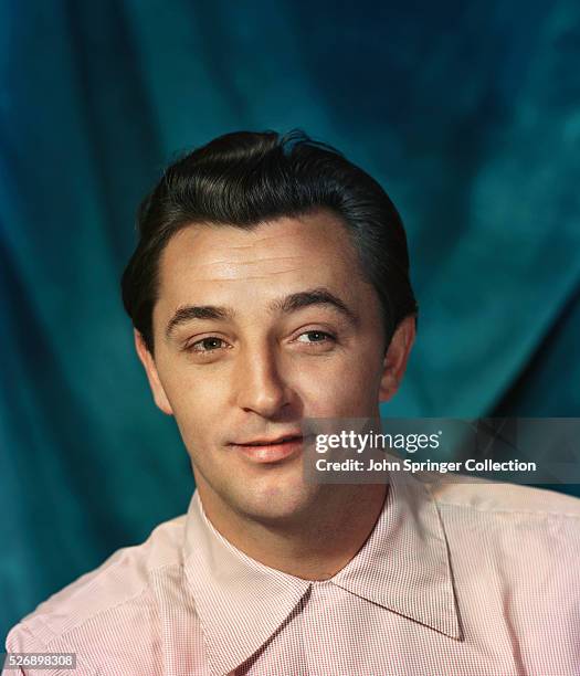 Head and shoulders of a young Robert Mitchum . He is smiling and wearing a white shirt. Undated color slide.