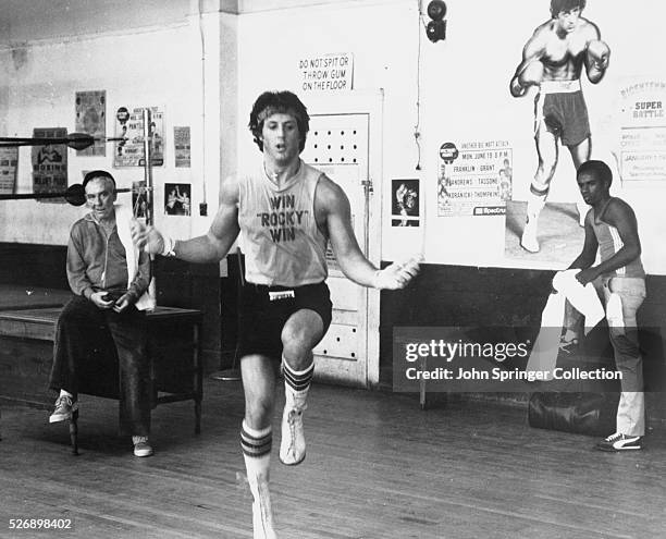 Training for a heavy weight title fight, Rocky Balboa skips rope under the watchful eye of his manager, Mickey , and trainer Johnny in Rocky II.