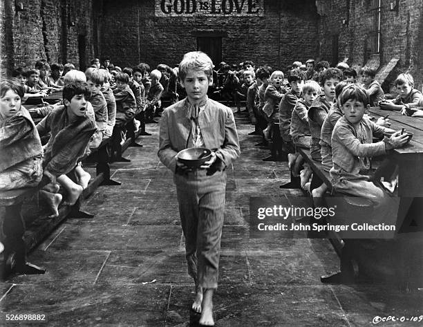 Oliver Twist boldly walks to the front of the orphanage dining hall to ask for more porridge in the 1968 musical film Oliver!, based on the novel...