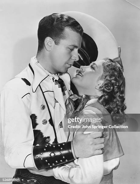 Actor Dick Powell embracing Priscilla Lane in costumes from the 1938 film Cowboy from Brooklyn.