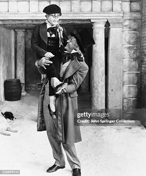 Changed Ebenezer Scrooge holds up Tiny Tim on Christmas morning in A Christmas Carol 1951.