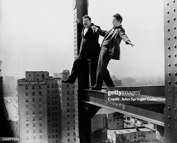 Stan and Ollie balance on a beam at a high rise construction site during a scene from the 1929 comedy Liberty.